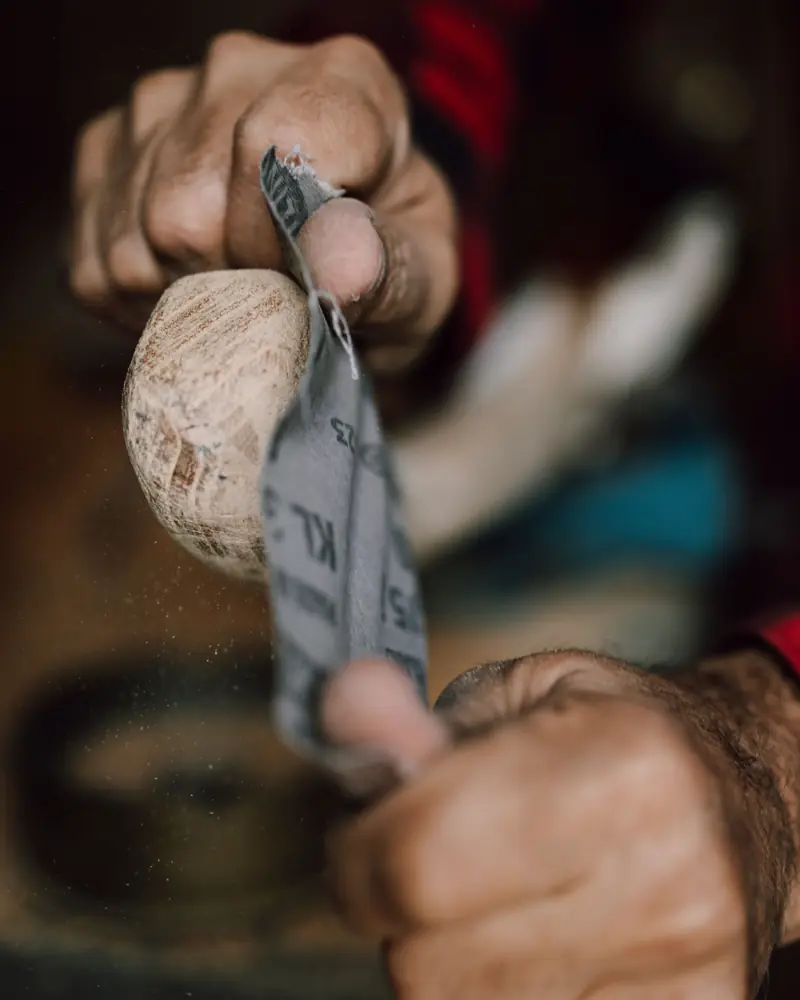 Ein Holzwerkstück wird von Hand mit Schleifpapier geschliffen
